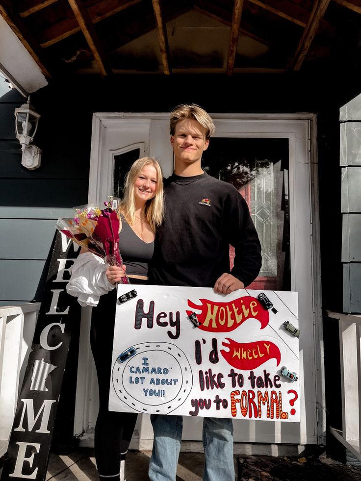 a man and woman standing in front of a house holding signs that read hey, i'm finally