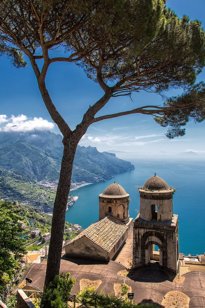 an old building on the side of a mountain with a tree in front of it