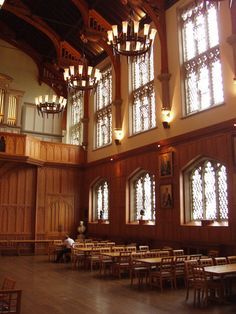 the inside of an old building with many tables and chairs in front of large windows