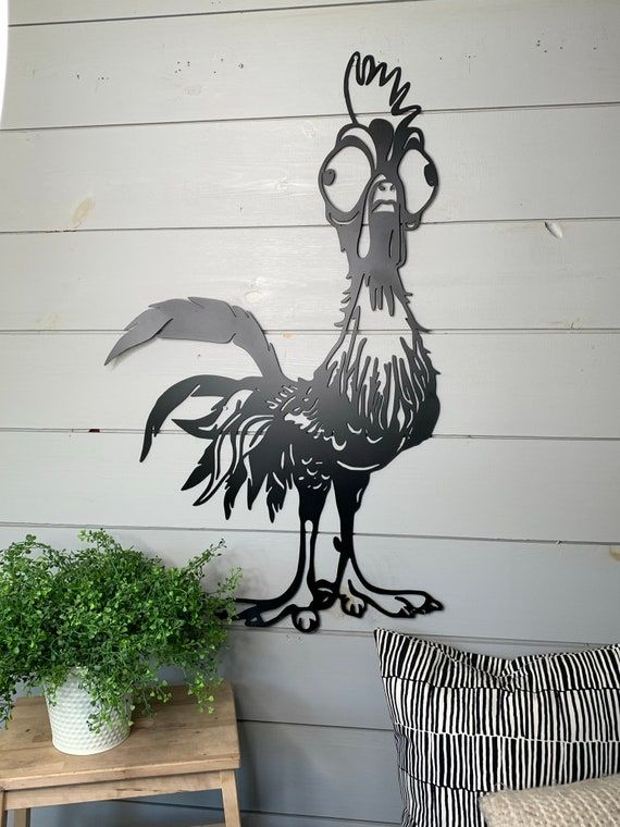 a rooster stencil on the side of a house with a potted plant next to it