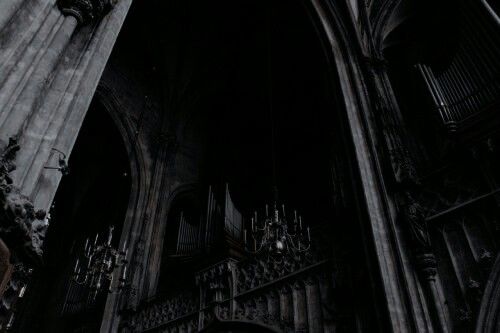 an old gothic church with columns and chandelier