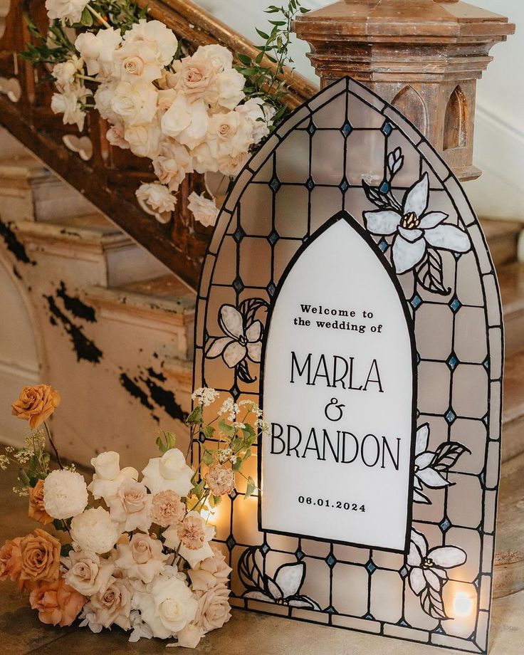 a stained glass window with flowers and candles on the ground next to it is a sign that says, welcome to marla & brandon