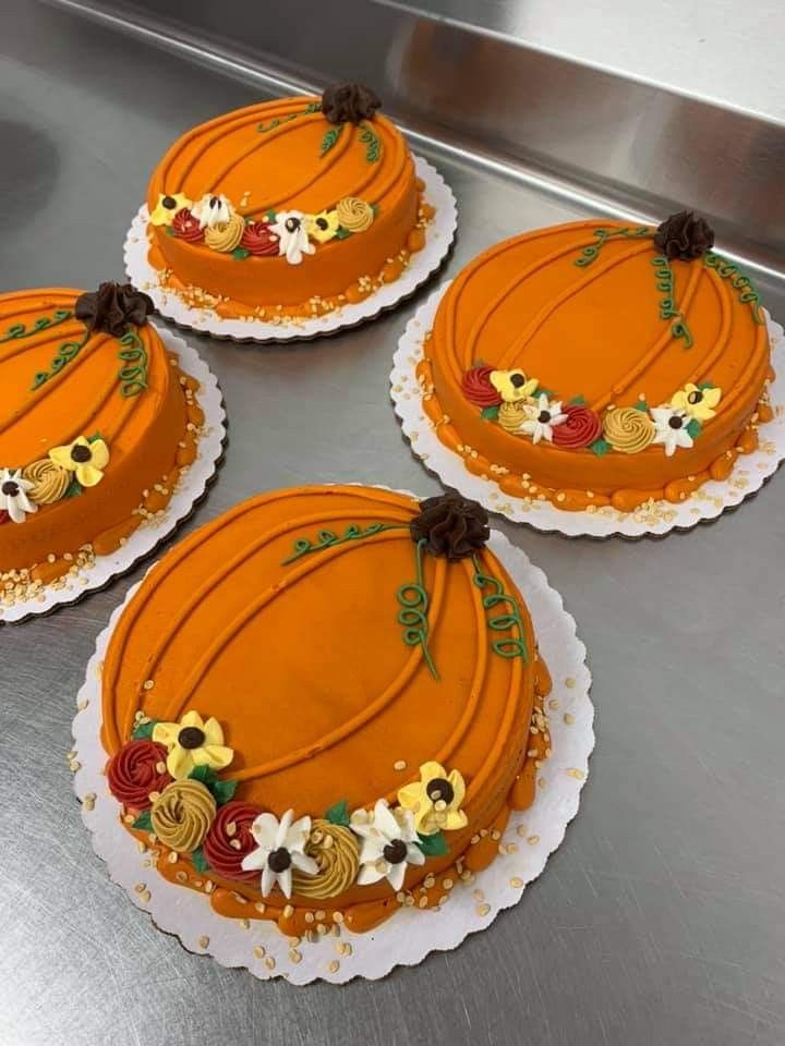 four cakes decorated with flowers and ribbons on top of a metal counter in a kitchen