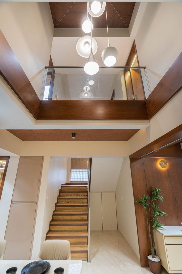 the interior of a house with stairs and lights hanging from it's ceiling beams