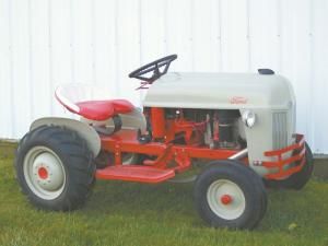 an old red and white farmall tractor parked in front of a white fenced off building