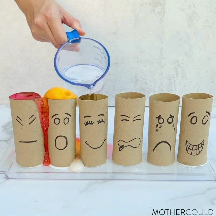 toilet paper rolls with faces drawn on them are being filled with liquid from a measuring cup