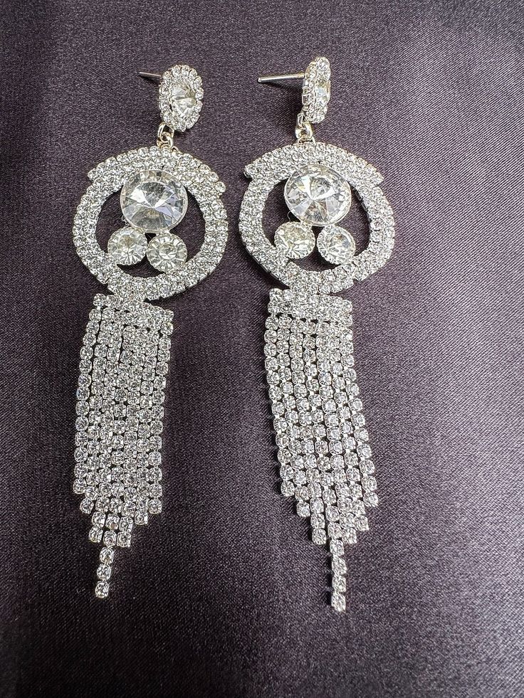 Embrace elegance with our sparkling rhinestone earrings, the perfect accessory to elevate any outfit for a night out. These dazzling dangle earrings effortlessly blend fashion and sophistication, adding a touch of glamour to your look. Make a statement with these stunning earrings that will enhance your style and make you stand out in any crowd. Elevate your ensemble and shine bright with these exquisite rhinestone earrings. Ready to be shipped Diamond White Crystal Earrings With Bling For Party, Party Dangle Diamond Earrings, Sparkling Silver Earrings For Glamorous Events, Silver Sparkling Earrings For Glamorous Events, Diamond White Crystal Earrings With Rhinestones For Party, Dazzling Diamond White Crystal Earrings For Party, Glamorous Diamond White Chandelier Earrings With Sparkling Stones, Sparkling Diamond White Chandelier Earrings For Party, Diamond White Sparkling Chandelier Earrings For Party