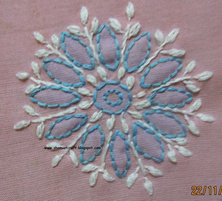 a blue and white embroidered flower on pink fabric