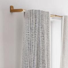 a curtain hanging on the side of a white wall next to a metal pole with gold handles