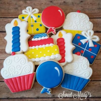 decorated cookies are arranged in the shape of a birthday cake and cupcakes on a wooden table