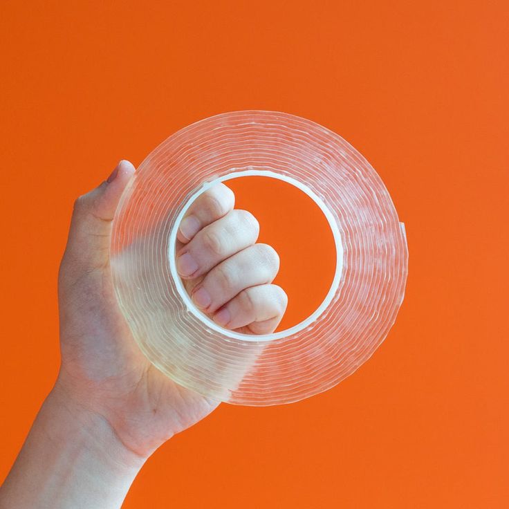 a hand holding a clear plastic object over an orange background