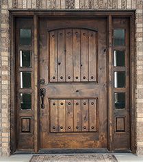 the front door is made of wood and has glass inserts on each paneling