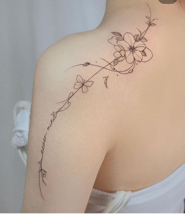 the back of a woman's shoulder with flowers on her left arm and an inscription written in cursive writing