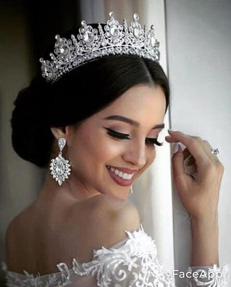 a woman wearing a tiara and holding her hand up to her face while looking out the window