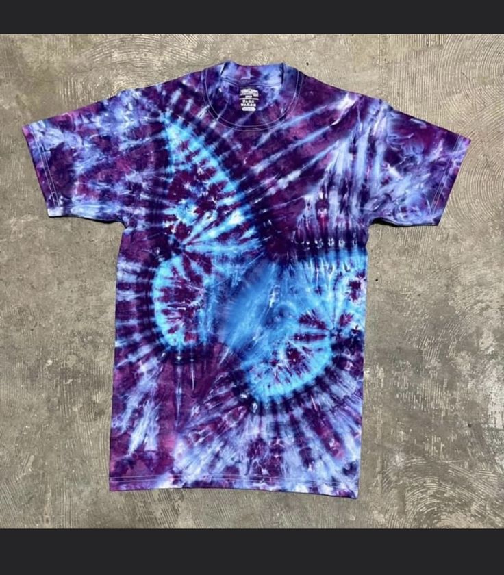 a purple and blue tie - dyed t - shirt sitting on top of a cement floor