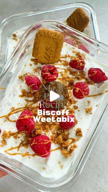 a person is holding up a dessert in a plastic container with strawberries and ice cream on top