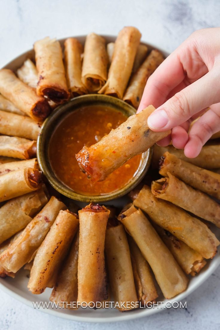 a person dipping sauce onto some food on a plate