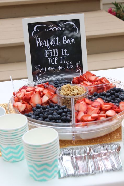 a table topped with plates and cups filled with fruit next to a sign that says parfait bar fill it top it