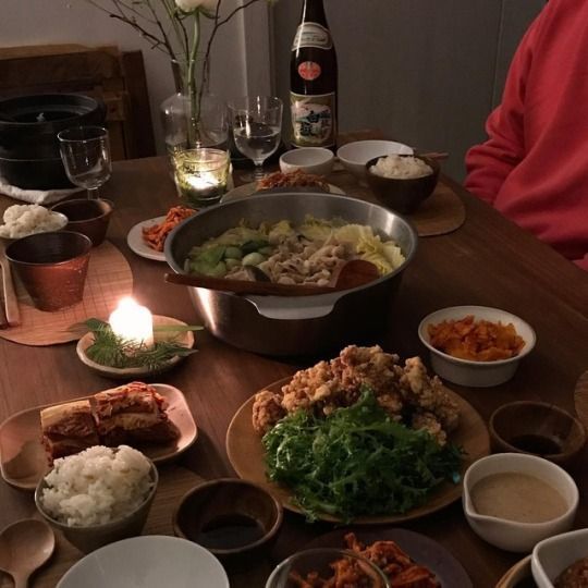 a person sitting at a table with many plates of food on it and a candle in front of them