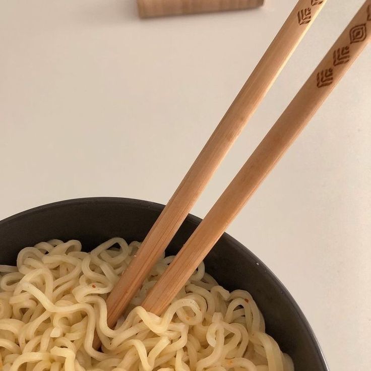 two chopsticks sticking out of a bowl of noodles