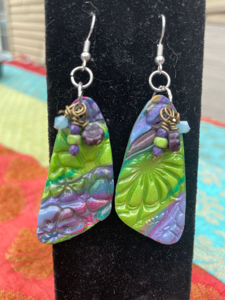 the earrings are made from polymer and have green, purple and yellow designs on them