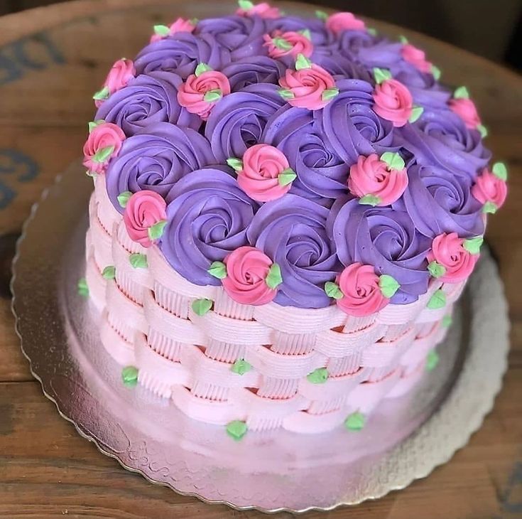 a cake with purple frosting and pink flowers on top is sitting on a plate