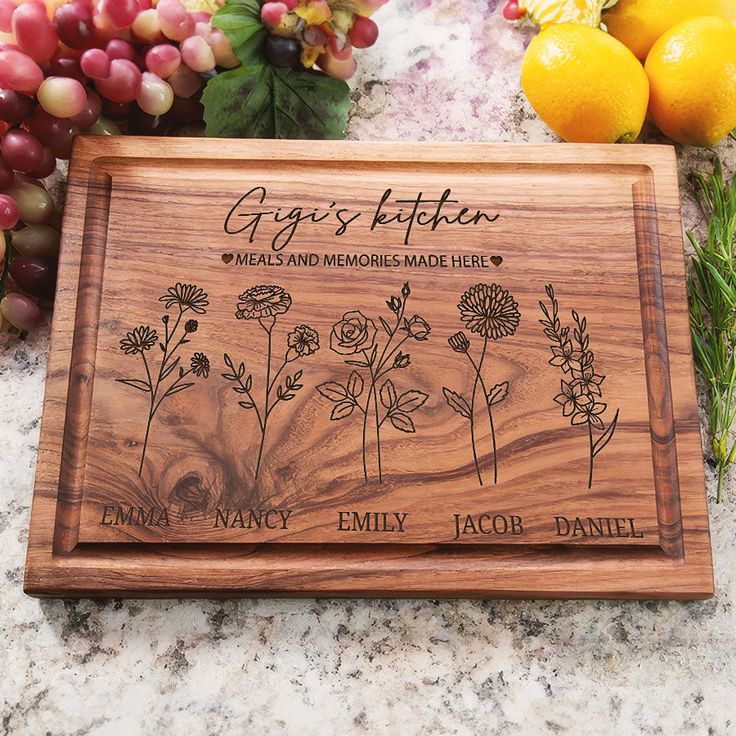 personalized cutting board with flowers and herbs engraved on the side, surrounded by grapes and lemons