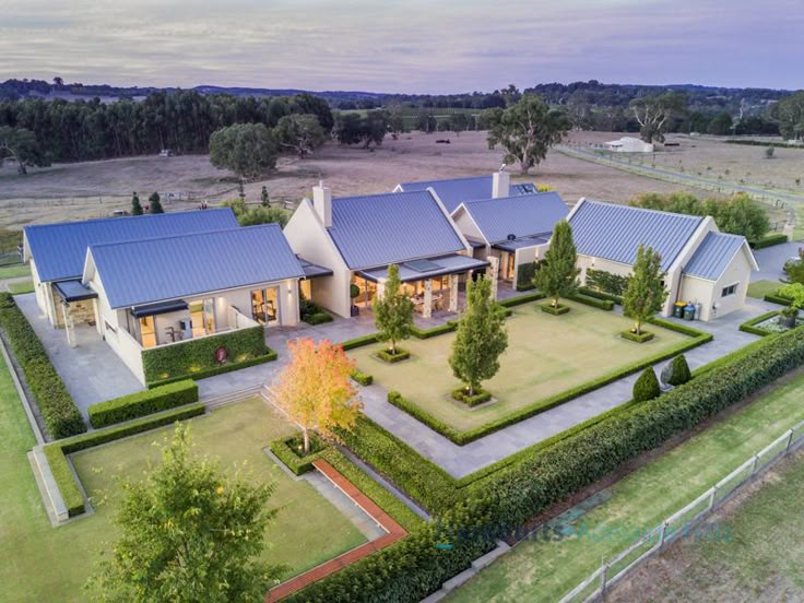 an aerial view of a large house surrounded by trees and hedges in the middle of a field