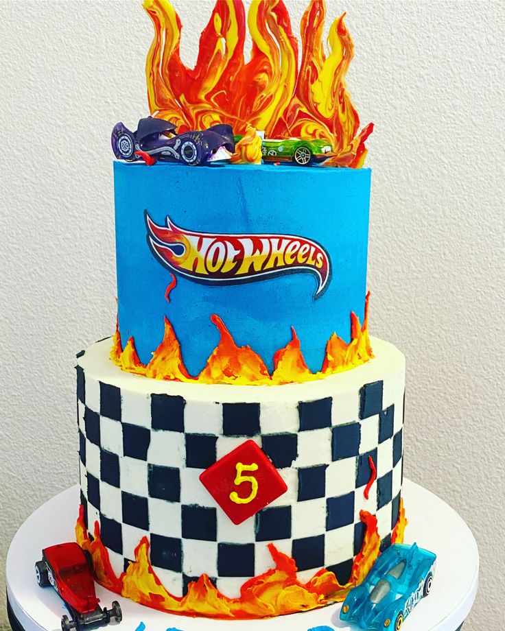 a three tiered cake decorated with hot wheels and flames on top of a table