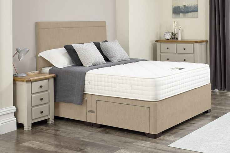 a bed sitting in a bedroom next to a night stand with two drawers on each side