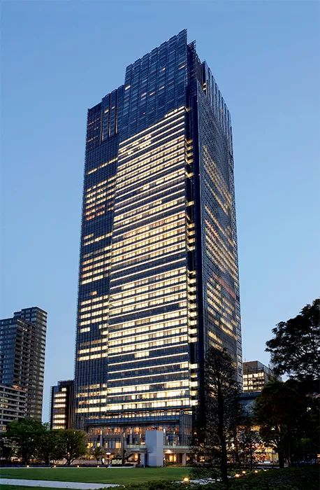 an office building lit up at night with skyscrapers in the background