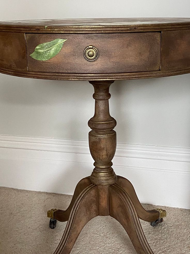 a wooden table with a green leaf painted on it's side and wheels to the bottom