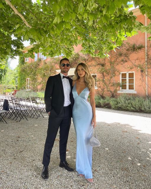 a man in a tuxedo standing next to a woman in a blue dress