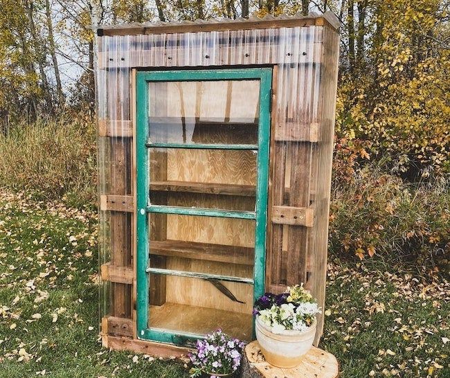 an outhouse made from pallet wood and old windows