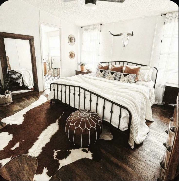 a bedroom with white walls and wood flooring has a cowhide rug on the floor