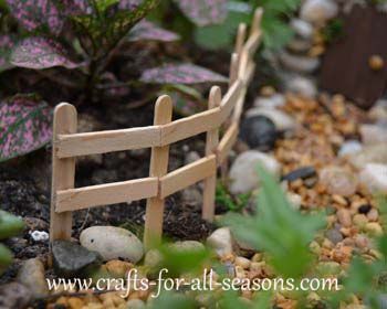 a small wooden fence sitting in the middle of some rocks and leaves on the ground