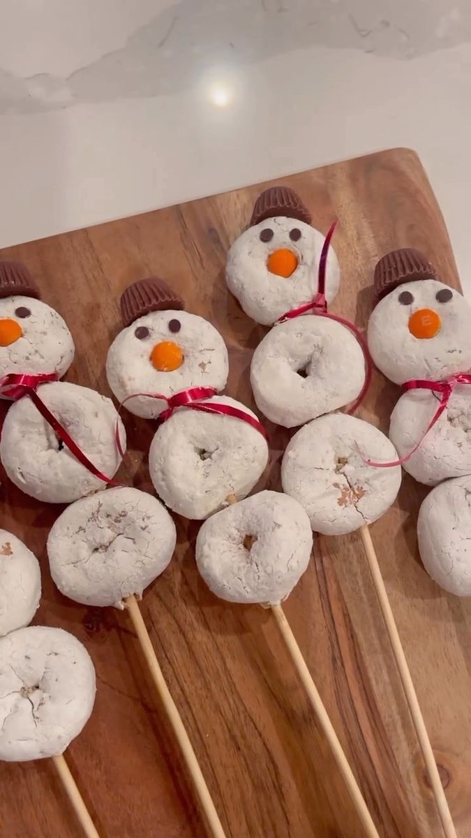 snowmen made out of doughnuts sitting on top of a wooden board