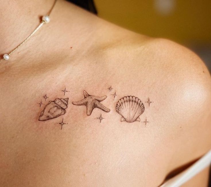 three seashells and starfish tattoo on the back of a woman's shoulder