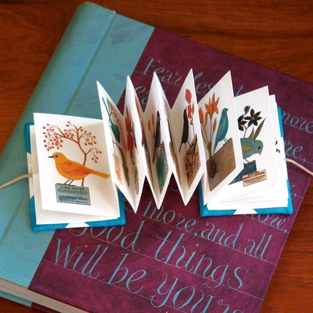 four folded cards sitting on top of a table next to an open book with the pages cut out