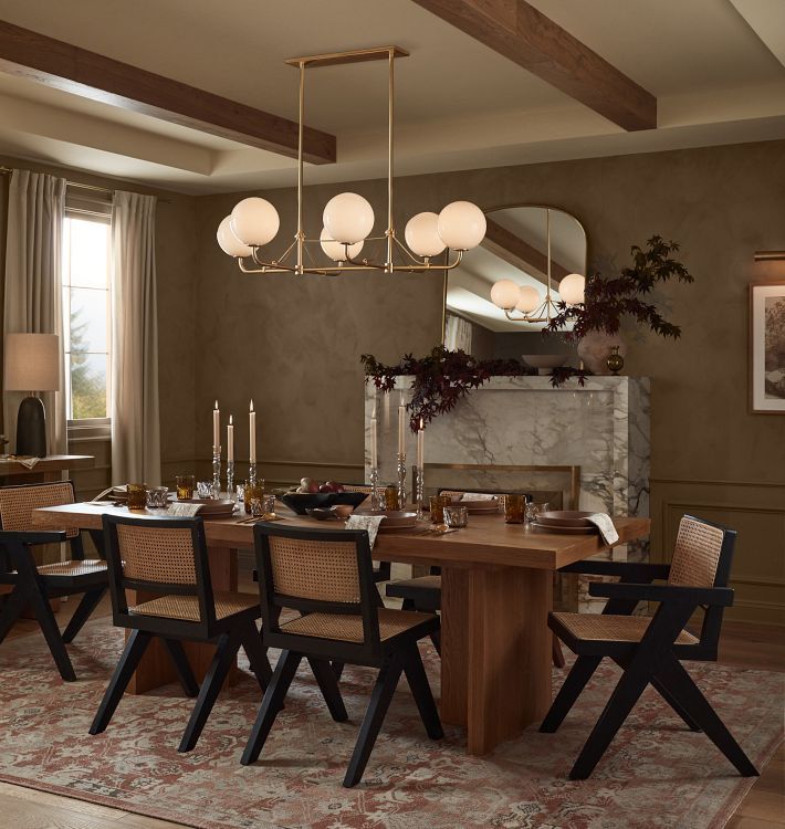 a dining room table and chairs with lights hanging from the ceiling