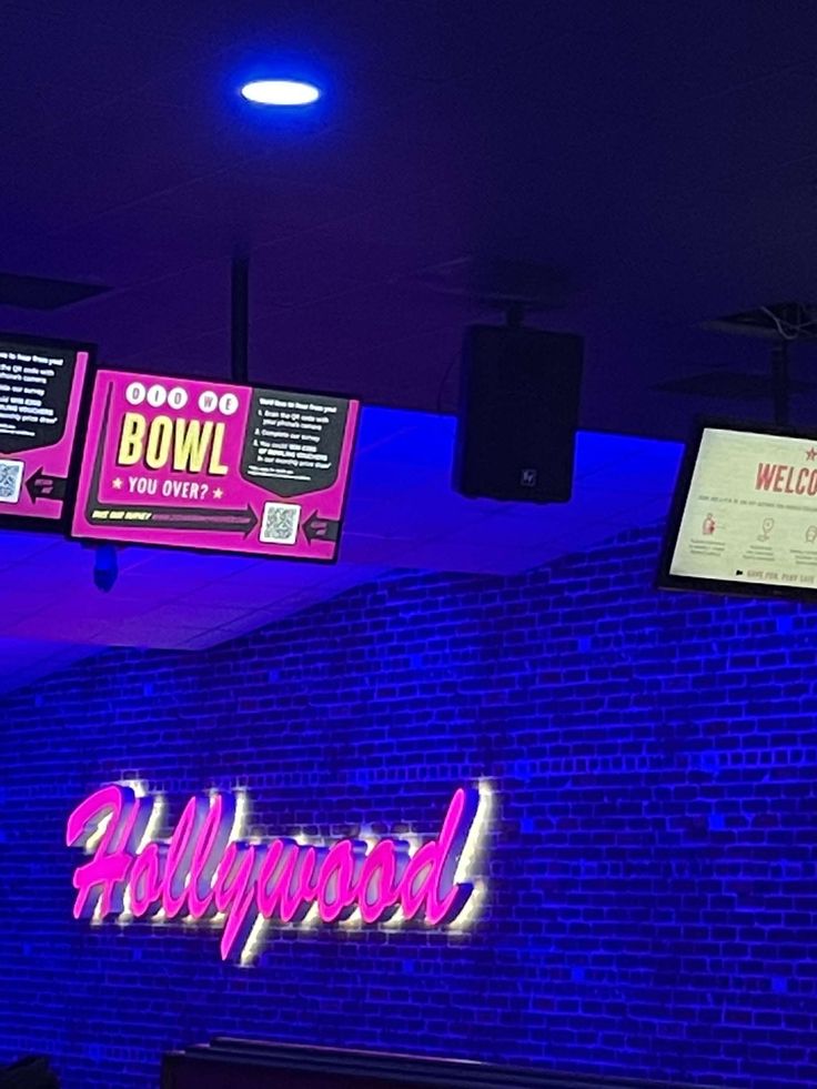 the neon sign above the bowling alley is lit up with blue lights and purple lighting