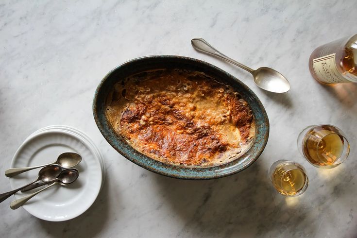 a bowl of food sitting on top of a table next to glasses and spoons