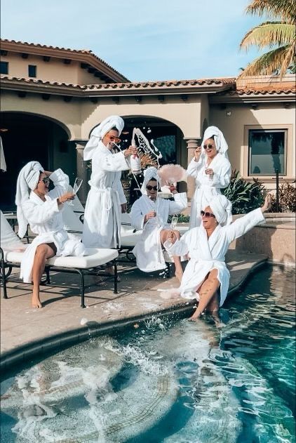 a group of people in white robes sitting next to a pool