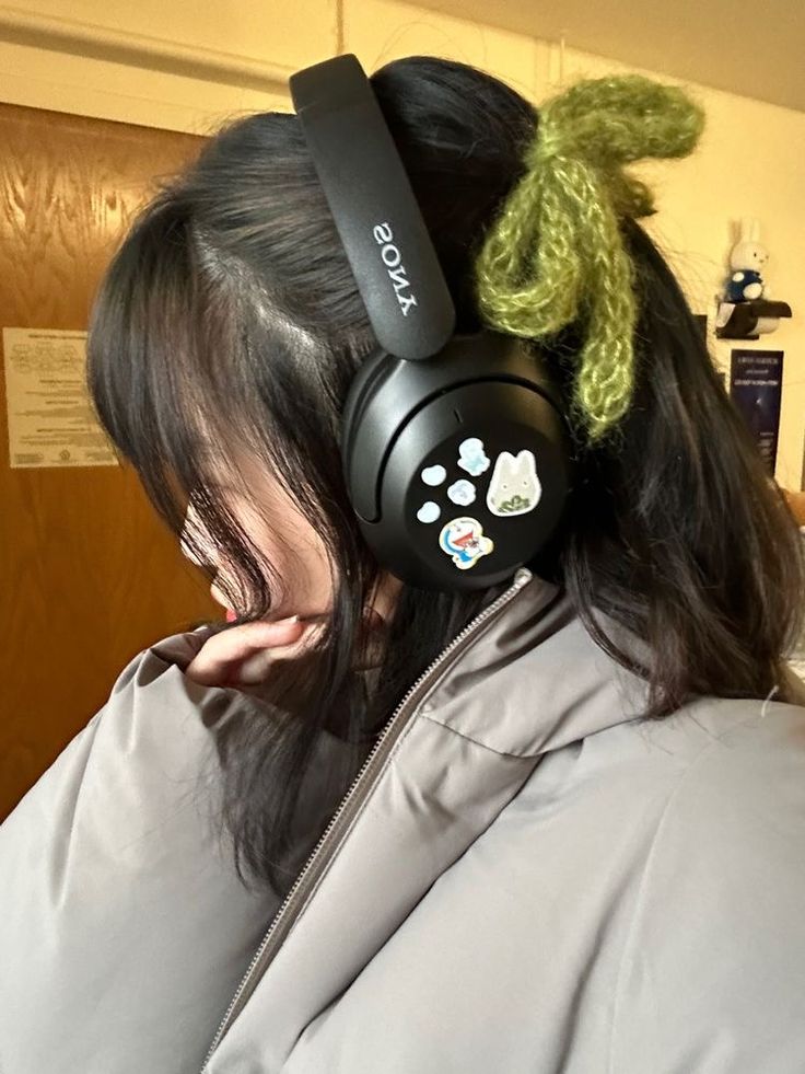 a woman with headphones on her ears is looking down at the ground while wearing a jacket