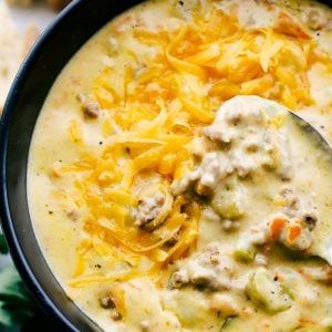 a close up of a bowl of soup with cheese and meat in it, on a table