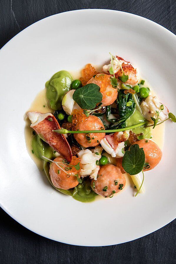 a white plate topped with shrimp and veggies on top of a black table