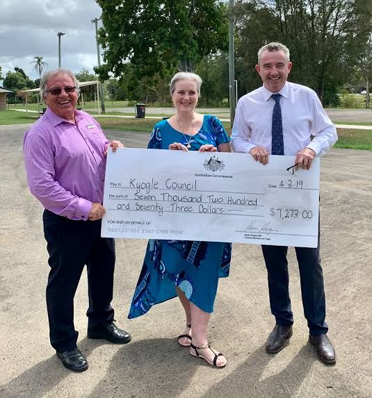 two men and a woman holding a large check for $ 1, 500 in the parking lot