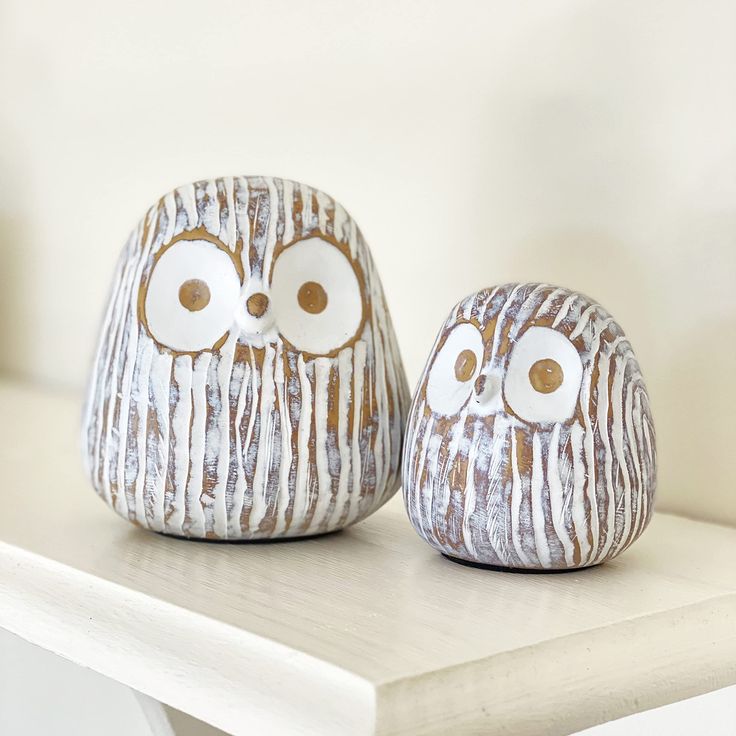 two ceramic owls sitting on top of a white table