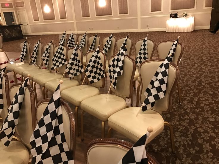 rows of chairs with black and white checkered flags on them in a banquet hall