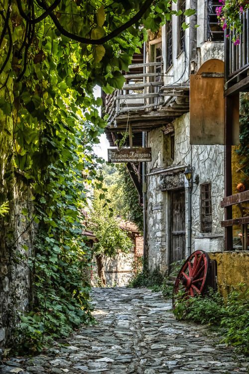 an old cobblestone street with stone buildings and greenery